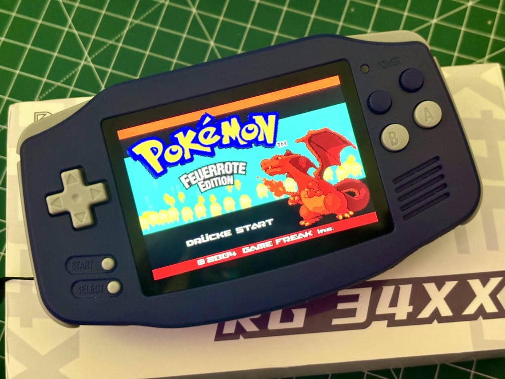 Anbernic RG34xx mit eingeschaltetem Pokémon liegend auf seiner Verpackung,